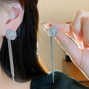 Close-up of sparkling zircon flower stud earrings with long elegant silver tassels