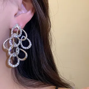 Detailed macro view of elegant silver rhinestone twisted waterdrop dangling earrings worn on ear