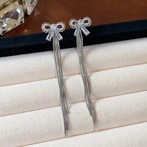 Detailed close-up of zircon bow earrings with long silver tassels on jewelry display