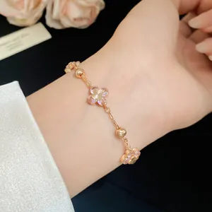 Detail shot of a delicate rose gold bracelet featuring pink cherry blossom zircon charms.