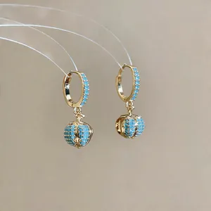 Detail showing 18k gold plated hoop earrings with vibrant blue pavé zircon beads.
