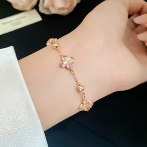 Elegant pink flower bracelet with golden beads and mother-of-pearl charms on wrist