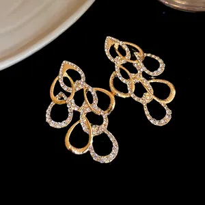 Close-up of gold-toned earrings with sparkling rhinestone distorted water drop design