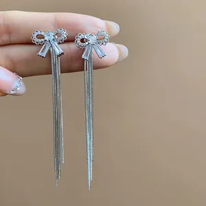 Detailed view of elegant silver bow earrings featuring sparkling zircon and long chain tassels