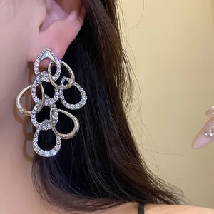 Detail view of exquisite sparkling rhinestone-encrusted twisted waterdrop earrings on ear