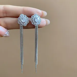 Close-up of elegant flower stud earrings with long silver tassel chains and sparkling zircons