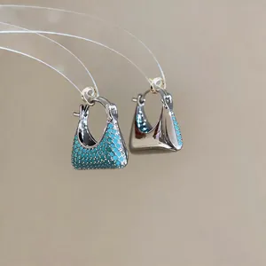 Detail view of 18k gold plated handbag-shaped earrings with vibrant turquoise zircon stones