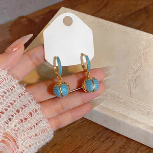 Detailed close-up of French retro gold plated earrings with turquoise globe dangles.