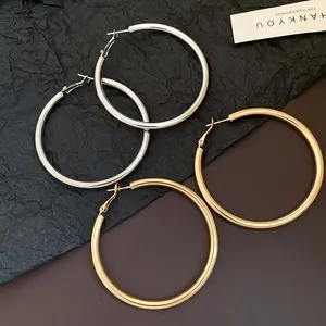 Detailed view of elegant gold and silver metallic hoop earrings on a textured surface