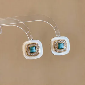 Detail of French vintage square earrings with green stone and gold plating finish.