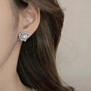 Close-up detail of a sparkling cubic zirconia floral ear clip on an ear