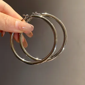 Close-up detail of large silver-colored metal hoop earrings with a high-shine polished finish.