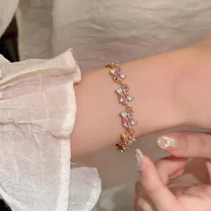 Primo piano di un bracciale in oro rosa con zirconi rosa marquise su un polso.