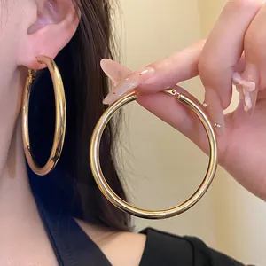 Detailed view of large gold-finished metal hoop earrings with a smooth polished surface.