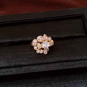 Detailed view of a sparkling zircon ear clip on a black textured jewelry display tray.