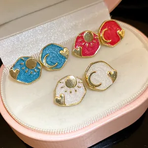 Close-up of vintage enamel sun moon heart stud earrings in blue pink and white