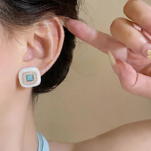 Close-up of vintage geometric square stud earrings with blue stone on model