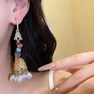 Elegant parrot-shaped earrings with rhinestones and pearl tassels shown on a model