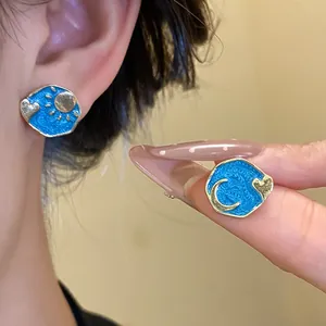 Detailed view of vintage blue enamel asymmetric sun and moon stud earrings