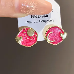 Close-up of vintage pink enamel stud earrings with sun moon and heart designs