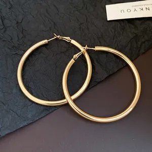 Close-up detail view of elegant large gold-finish hoop earrings with a polished surface.