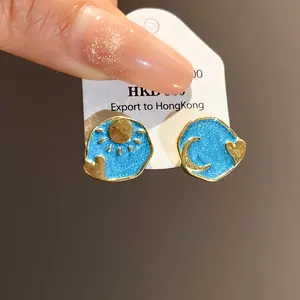 Close-up detail of vintage style enamel earrings featuring sun, moon and heart motifs
