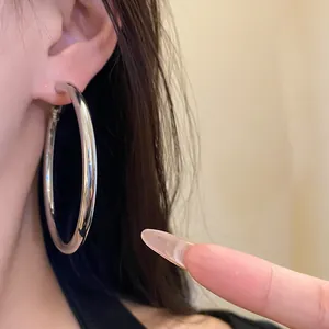 Close-up detail of large polished silver hoop earrings worn on ear for an elegant style