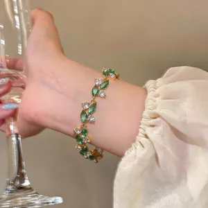 Dettaglio di un elegante bracciale placcato oro decorato con zirconi verdi e bianchi