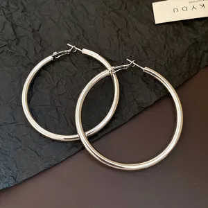 Close-up of large polished silver hoop earrings with a minimalist vintage design style.
