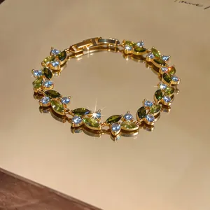 Vista macro dettagliata di un bracciale placcato oro con zirconi verdi e blu brillanti