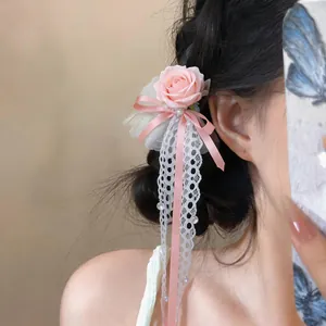 Nahaufnahme einer eleganten rosa Rosen-Haarklammer mit weißer Spitze und Bändern