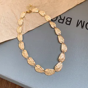 Vista detallada de un collar dorado con placas ovaladas de metal texturizado moderno.