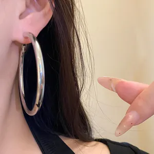Detailed close-up view of a large silver metal hoop earring worn on a female ear