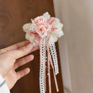 Detaillierte Ansicht einer rosa Rosen-Haarklammer mit Spitzenbändern und Perlenquasten-Design
