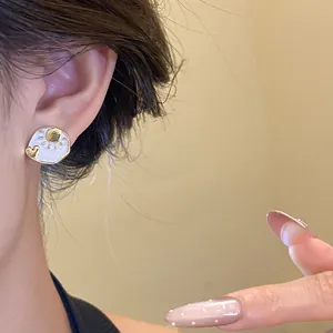 Detailed view of elegant gold-tone sun and moon stud earrings on an Asian model ear.