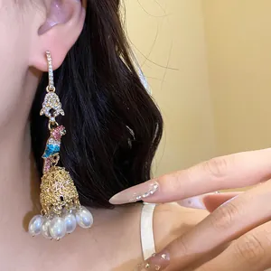 Detailed view of ornate parrot drop earrings with faux pearls and sparkling stones