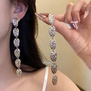 Detalle de los pendientes largos plateados con una textura única de metal arrugado