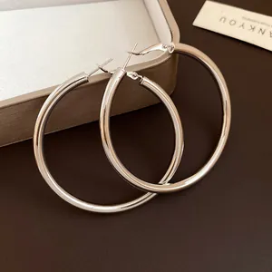 Close-up of minimalist silver-toned metal hoop earrings on a dark textured surface