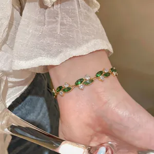 Dettaglio di un bracciale placcato oro con foglie di zircone verde sul polso