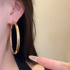 Macro view of large chunky gold-colored metal hoop earrings for a stylish minimalist look
