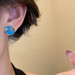 Detail shot of vintage blue enamel stud earrings with golden sun and heart motif