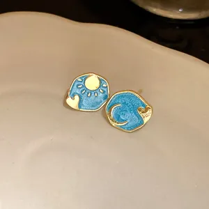 Detailed view of vintage blue enamel sun and moon stud earrings with gold heart accents