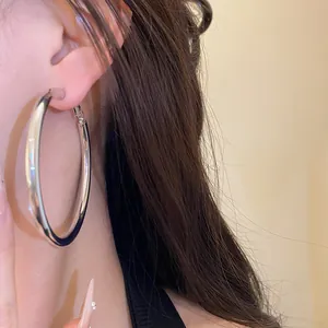Close-up of a large silver metal hoop earring showing the elegant worn effect on the ear