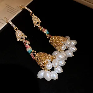 Detailed close-up of parrot drop earrings featuring rhinestones and white pearl tassels