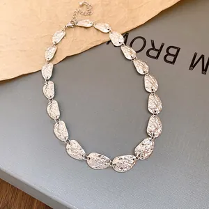 Detalle de collar metálico plateado con textura ovalada martillata de estilo minimalista