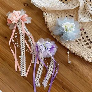 Detailansicht eleganter Spitzenblumen-Haarspangen in Rosa, Lila und Blau mit Bändern