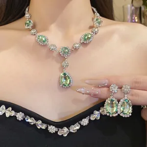 Sparkling green pear-shaped jewelry set featuring necklace and earrings on a model.