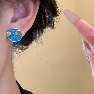 Detailed close-up showing a vintage blue enamel sun and cloud stud earring worn on the ear.