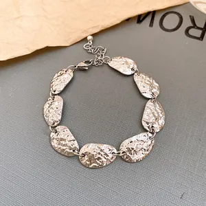 Vista detallada de una pulsera plateada con placas ovaladas martilladas y ajustable.