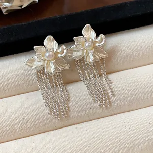 Detailed macro view of silver floral earrings with elegant pearl centers and tassels